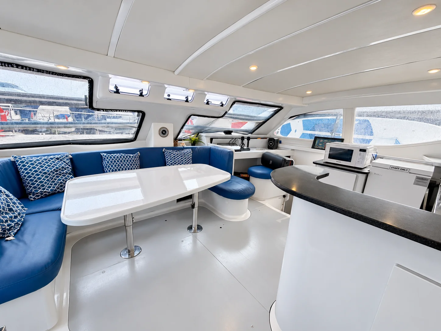 One Lotus indoor saloon with blue seating, dining table and galley